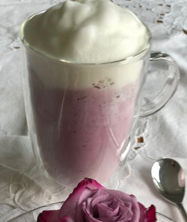 Himbeer-Latte in durchsichtigem Glas mit Milchschaum